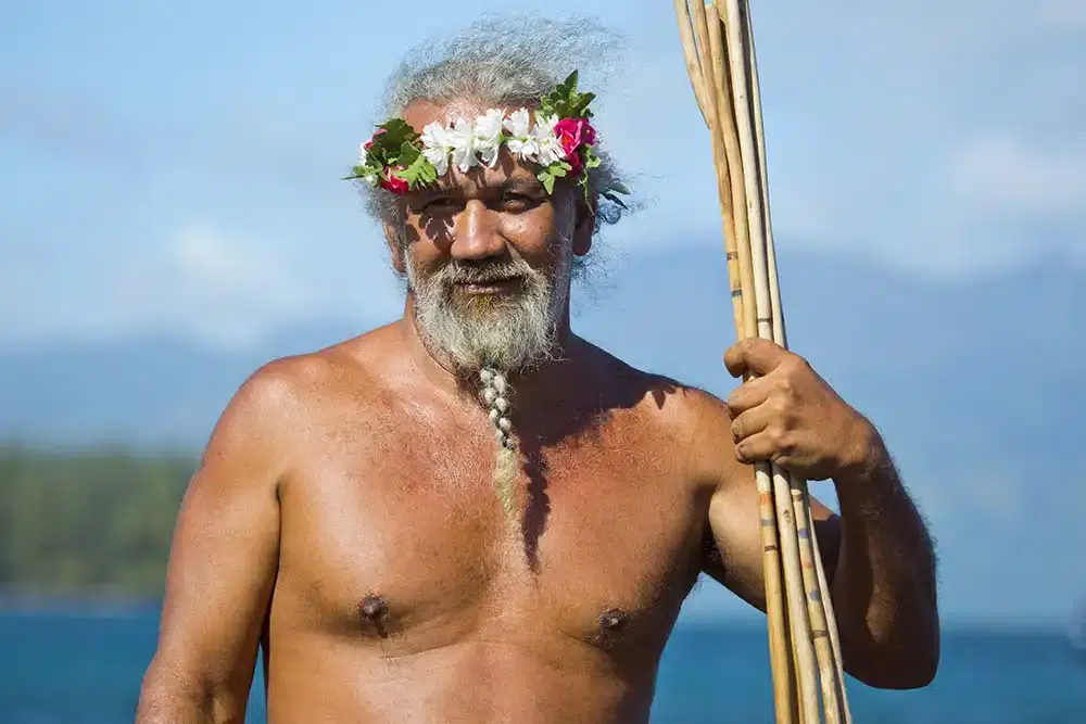 Homme tahitien avec lance traditionnelle avec un guide de voyage