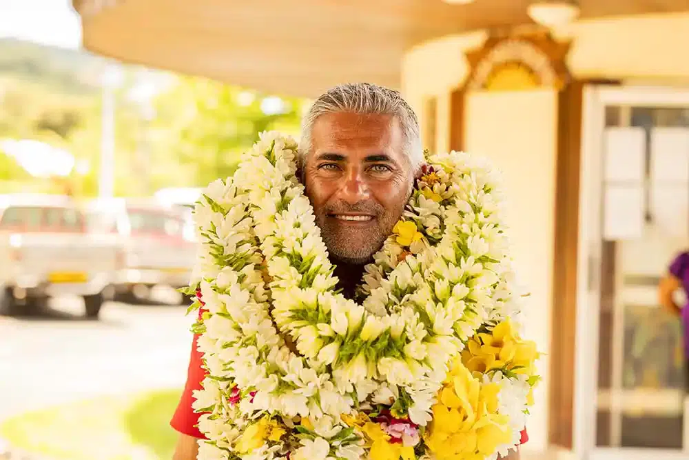 Senior man warmly welcomed with flower leis in Tahiti