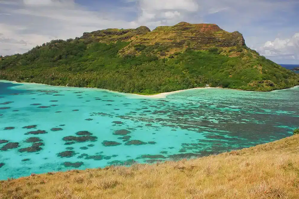 Volcanic hillside rising above the turquoise lagoon of Mangareva